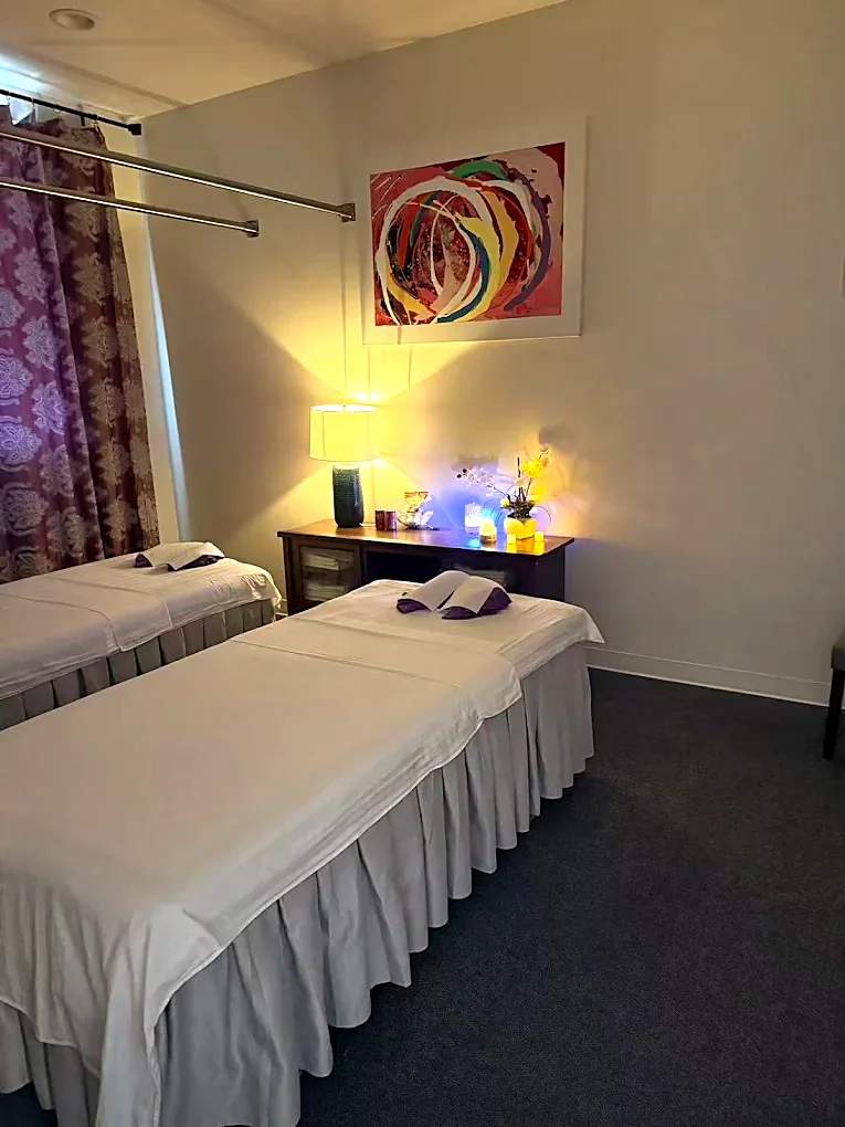 The couples room at Spring Massage — two massage tables made up side by side under warm lamplight